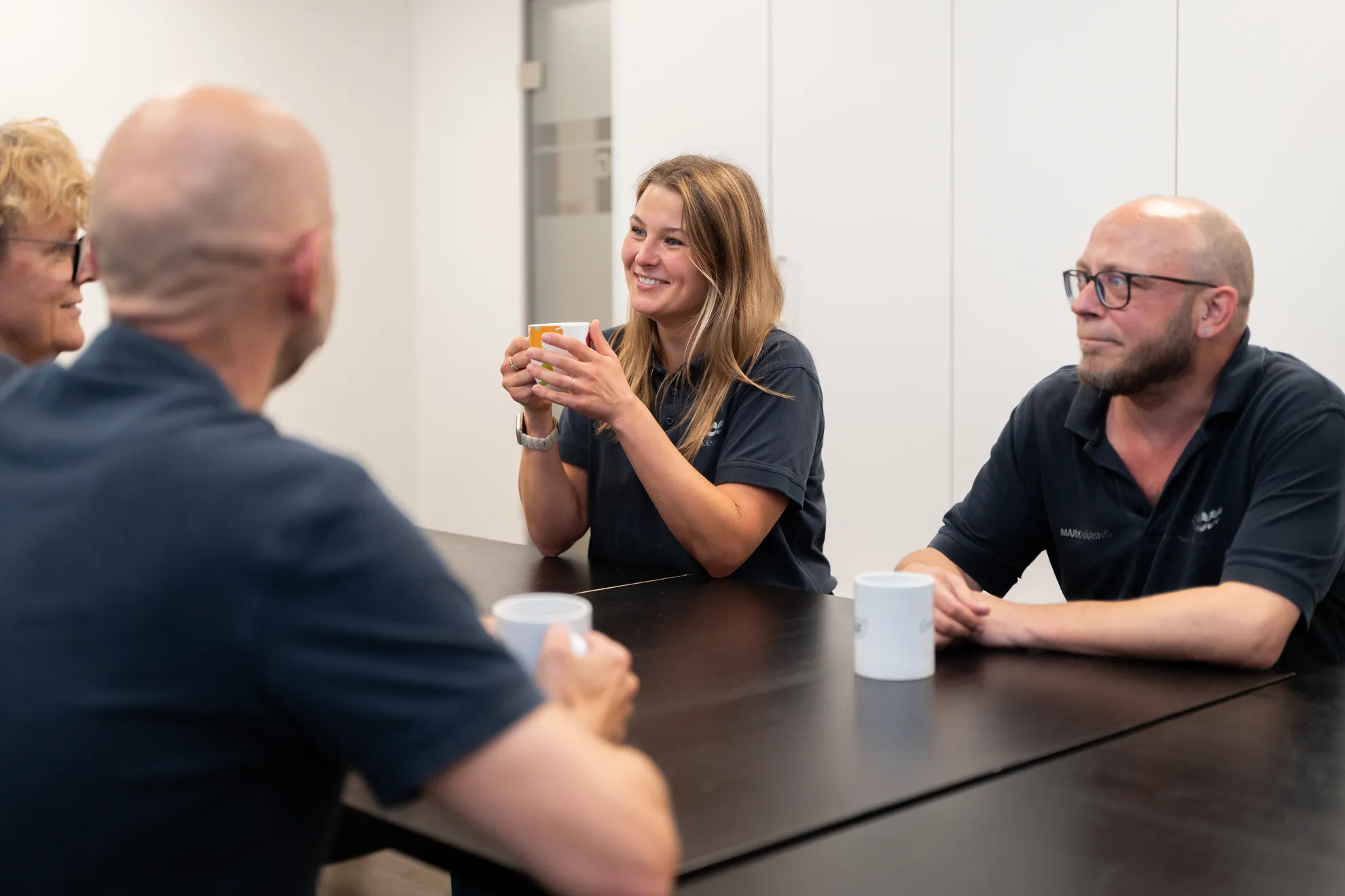 Vier Teammitglieder sitzen im Pausenraum und lachen